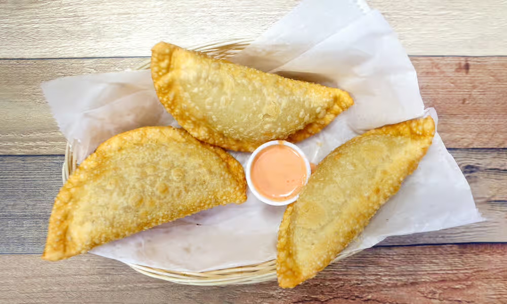 Crispy fried empanadas in a basket with dipping sauce
